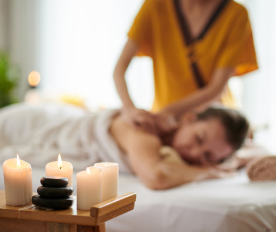 Woman Getting Back Massage Burning candles in spa salon and woman getting back massage in background